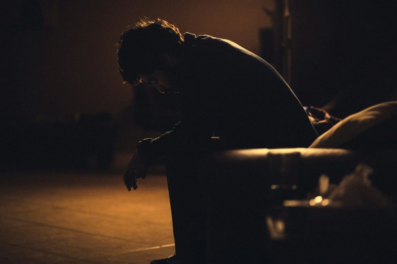 depressed man sitting alone in the dark on his couch